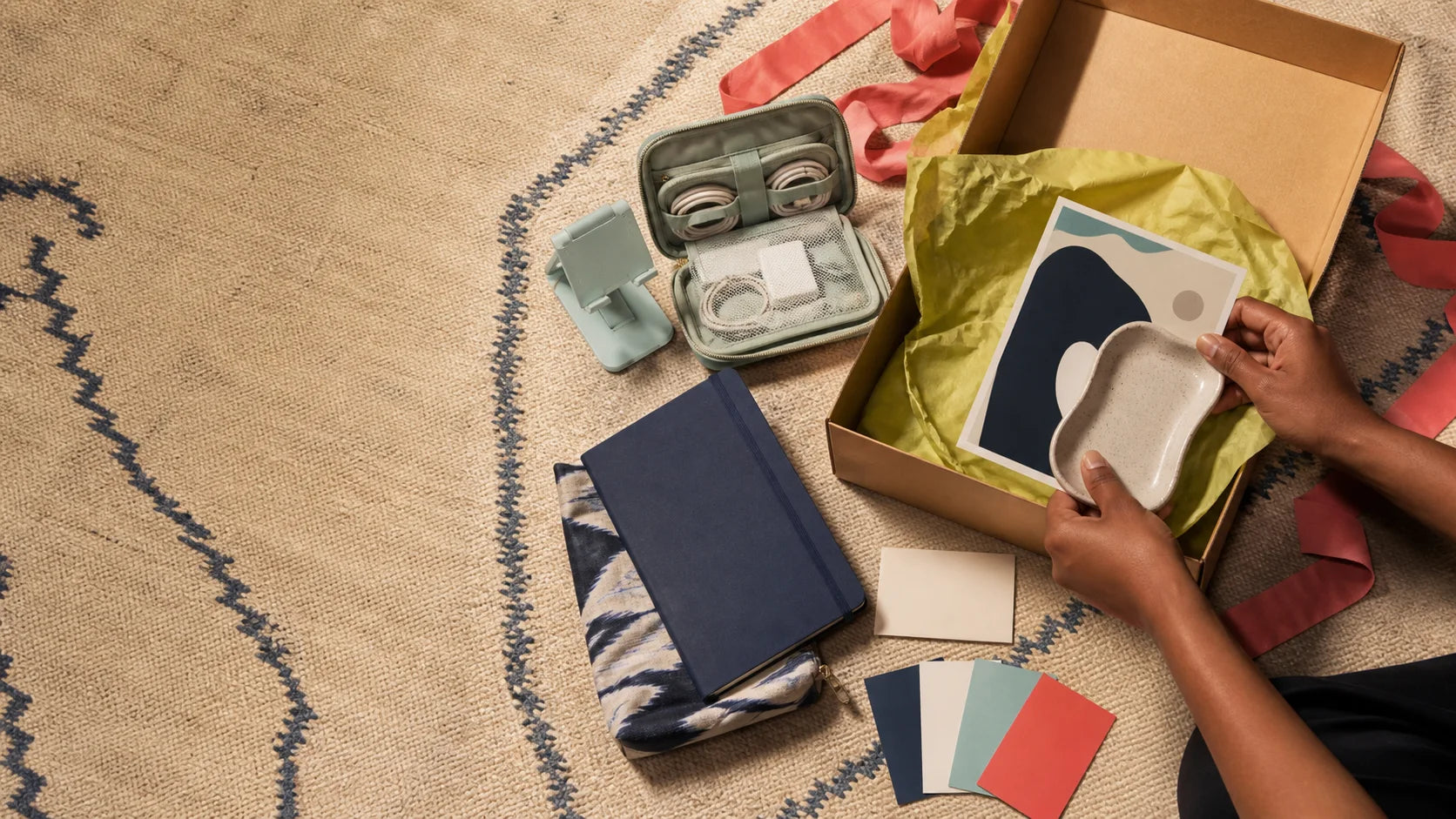 Hands assembling useful unbranded objects into a group gift box