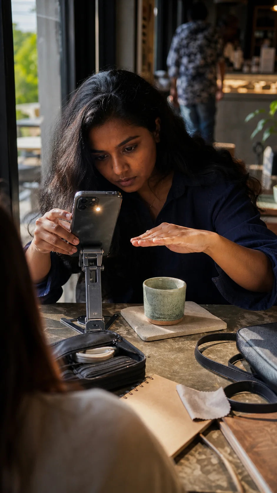 Indian creator framing a ceramic cup with a phone on a mechanical stand at a Pune cafe