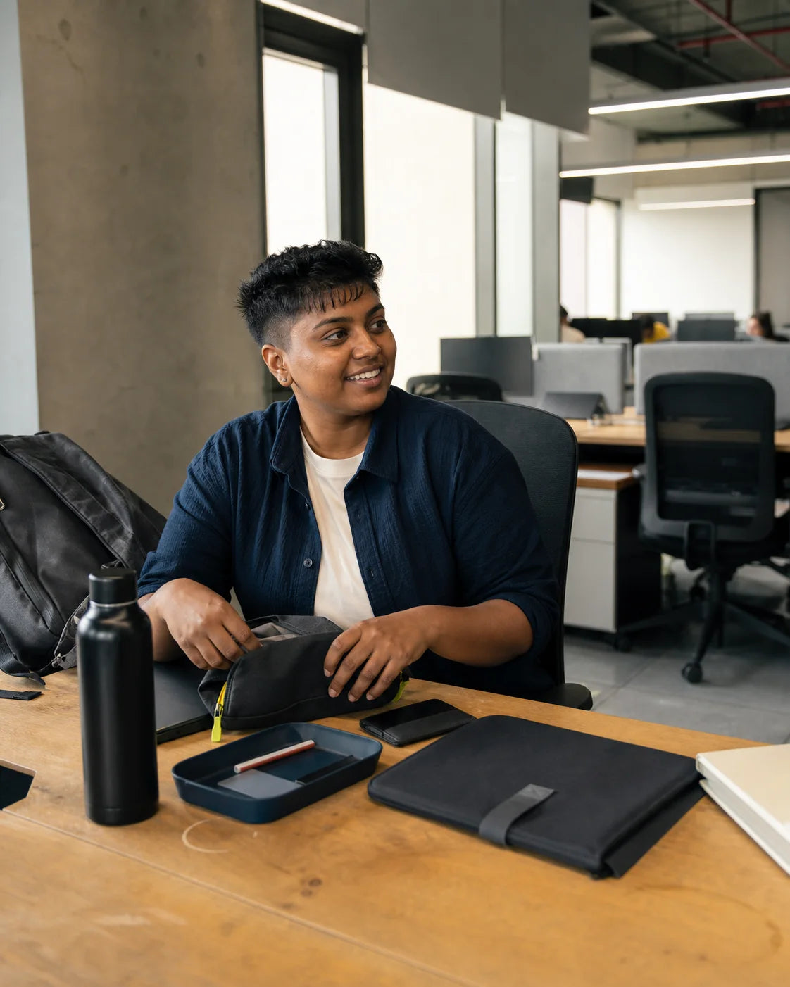 Indian young professional unpacking a laptop sleeve, cable pouch and desk tray at a first office