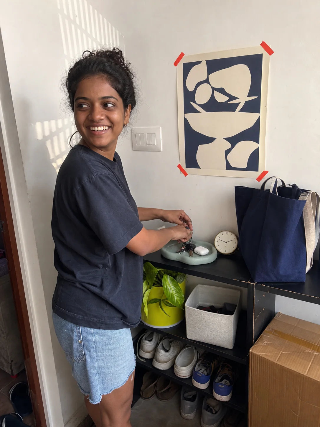 Indian young renter arranging a wall-safe abstract print and entryway tray