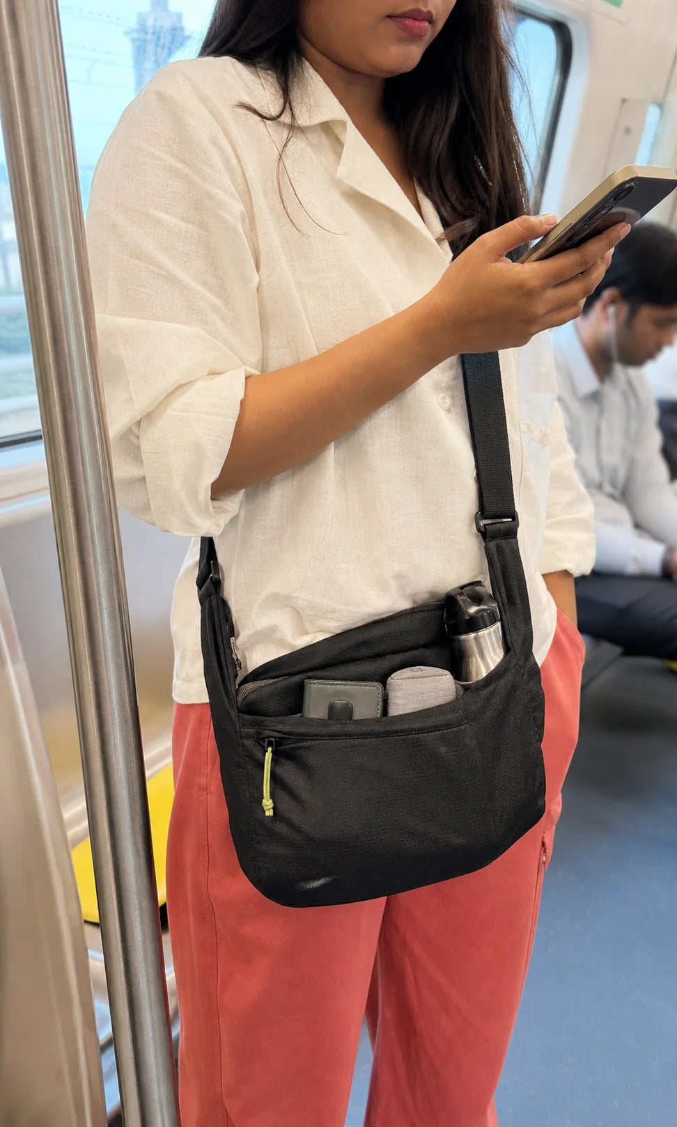 Indian Metro commuter using a compact sling with bottle and small essentials visible